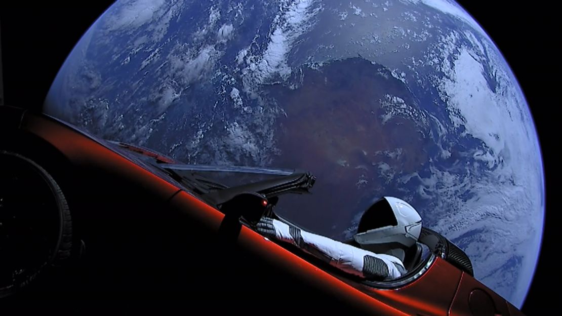 A dummy in a spacesuit is seen behind the wheel of Elon Musk's red Tesla sports car as it floats in space.