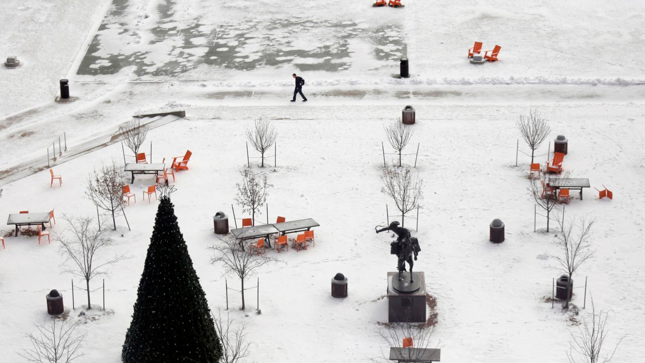 A man walks through snow-covered Barney Allis Plaza in Kansas City, Missouri.