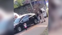 toddler with hands up walking to police