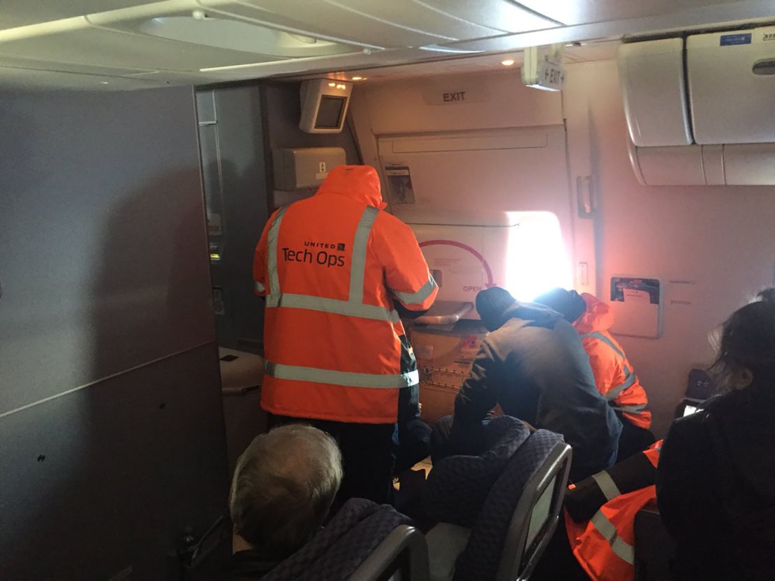 Passenger Steven Lau posted this photo of United workers trying to fix an emergency exit door.