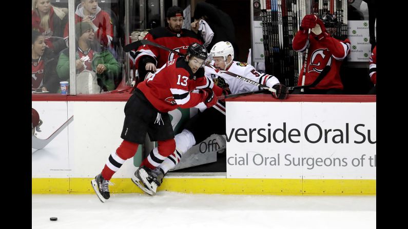 Chicago Blackhawks defenseman Connor Murphy gets checked into the New Jersey Devils bench by center Nico Hischier during the third period of an NHL hockey game on January 14 in Newark, New Jersey.
