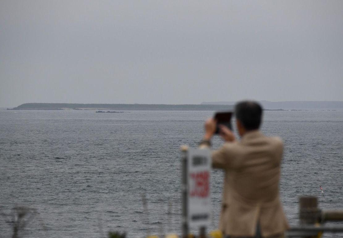 A tourist takes pictures of an islet making up part of the Habomai Islands at Cape Nosappu, a point on the Nemuro peninsula, Hokkaido prefecture. 