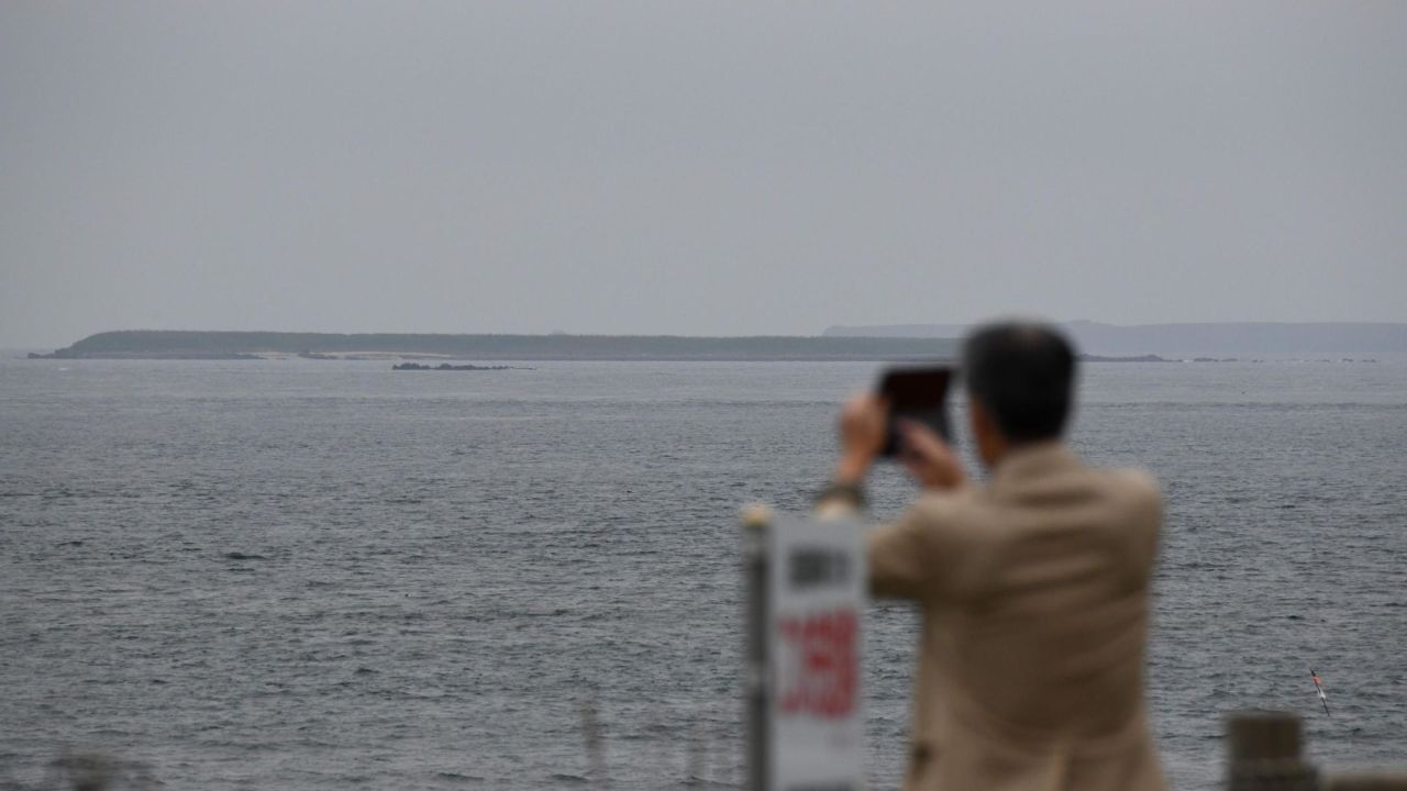 A tourist takes pictures of an islet making up part of the Habomai Islands at Cape Nosappu, a point on the Nemuro peninsula, Hokkaido prefecture. 