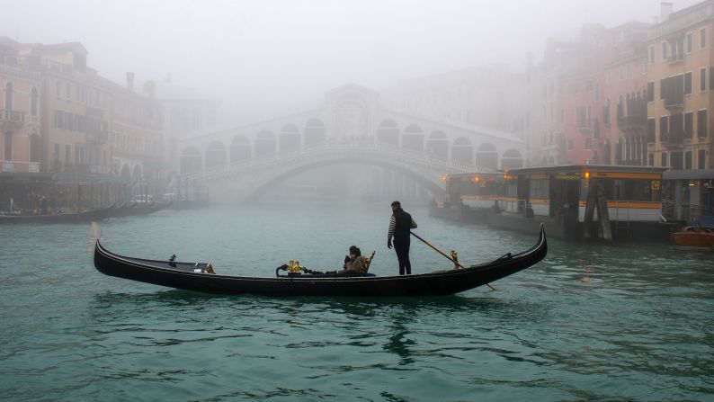 <strong>Venice, Italy: </strong>With the Grand Canal and Rialto Bridge shaded in fog, a gondola sails through the Venice waters.  