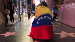 A woman with a Venezuelan flag wrapped around her shoulders kneels behind a paper star reading "Juan Guaido President of Venezuela" placed on the Hollywood Walk of Fame during a demonstration held by Venezuelans in support of Guaido in Hollywood on January 23, 2019. - The United States and major South American nations recognised Venezuelan opposition leader Juan Guaido as interim leader on January 23 while the EU called for free elections to restore democracy, leaving President Nicolas Maduro increasingly isolated. (Photo by Javier TOVAR / AFP)        (Photo credit should read JAVIER TOVAR/AFP/Getty Images)