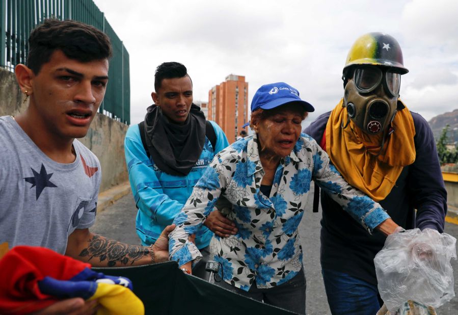 Opposition supporters react to tear gas as they take part in the Caracas rally on January 23. Sporadic clashes erupted, but Maduro's military response to the protests seemed more measured than in the past.