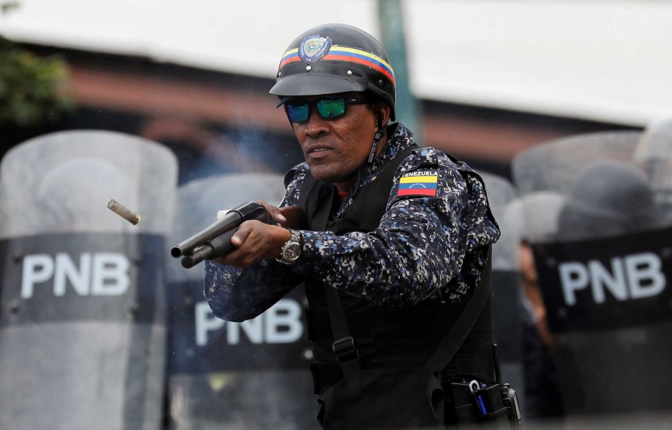 A National Police officer fires rubber bullets in Caracas.