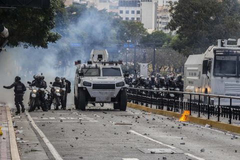Security forces stand in a street full of stones after clashing with demonstrators in Caracas.