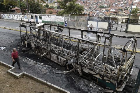 A man walks by a bus that had been set on fire in Caracas.
