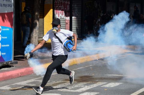 An opposition demonstrator runs with a tear-gas canister on January 23.