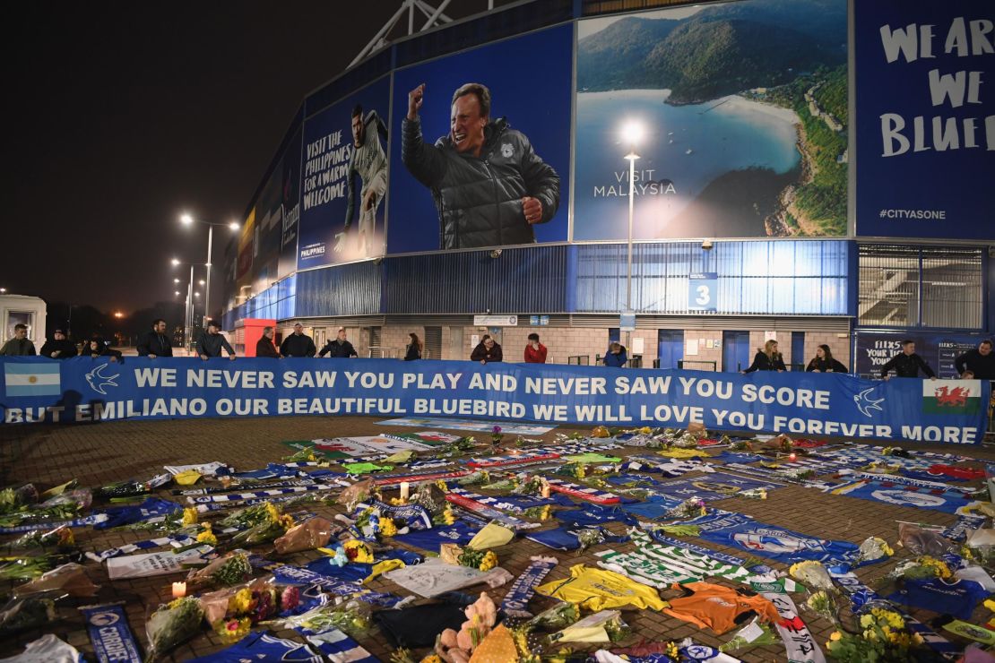 Cardiff City fans unveil a flag in front of tributes for their forward Emiliano Sala after the search for the missing footballer and pilot was called off.