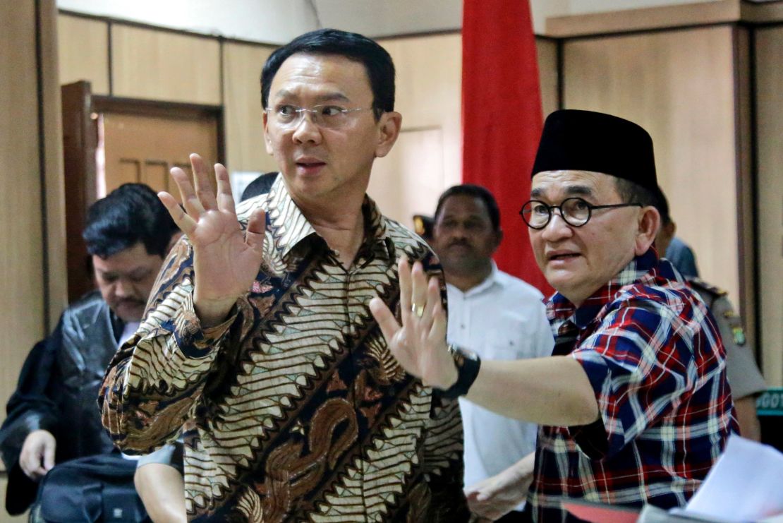 Jakarta Governor Basuki Tjahaja Purnama, popularly known as "Ahok" (left) and his campaign spokesman Ruhut Sitompul (right) wave to photographers after his trial for blasphemy at the North Jakarta District Court in Jakarta on December 13, 2016.