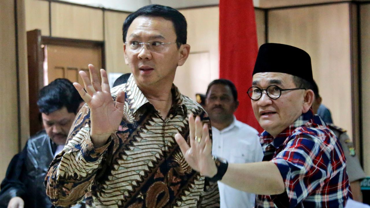 Jakarta Governor Basuki Tjahaja Purnama, popularly known as "Ahok" (left) and his campaign spokesman Ruhut Sitompul (right) wave to photographers after his trial for blasphemy at the North Jakarta District Court in Jakarta on December 13, 2016.