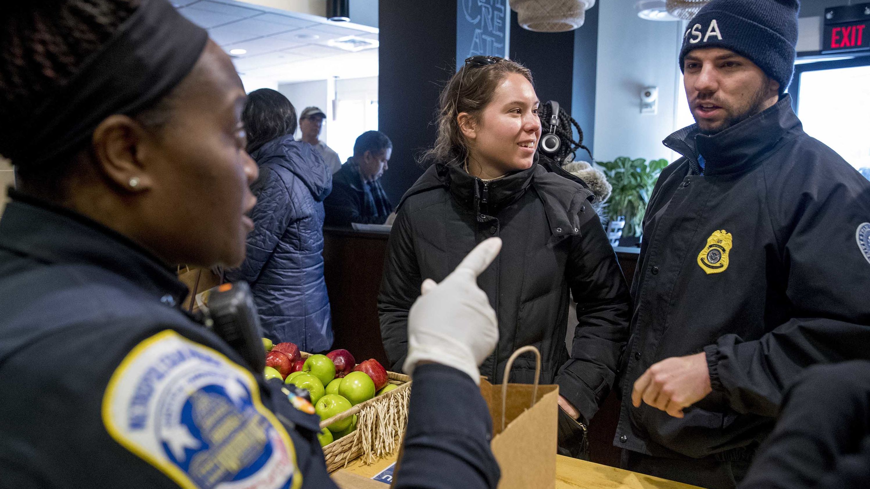 Metropolitan Police Officer and volunteer Adriane Benson, left, takes a food order for Shane Smith, a TSA agent, right, as he and other furloughed government workers affected by the shutdown receive free food and supplies at World Central Kitchen, the not-for-profit organization started by Chef Jose Andres, Tuesday, Jan. 22, 2019 in Washington. 