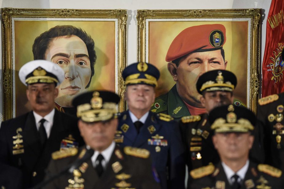 Portraits of former Venezuelan leaders Simon Bolivar and Hugo Chavez hover in the background as Venezuelan Defense Minister Vladimir Padrino Lopez, bottom left, addresses a news conference in Caracas on Thursday, January 24. Venezuela's top military officials swore their allegiance to Maduro after other nations recognized Guaido as head of state.