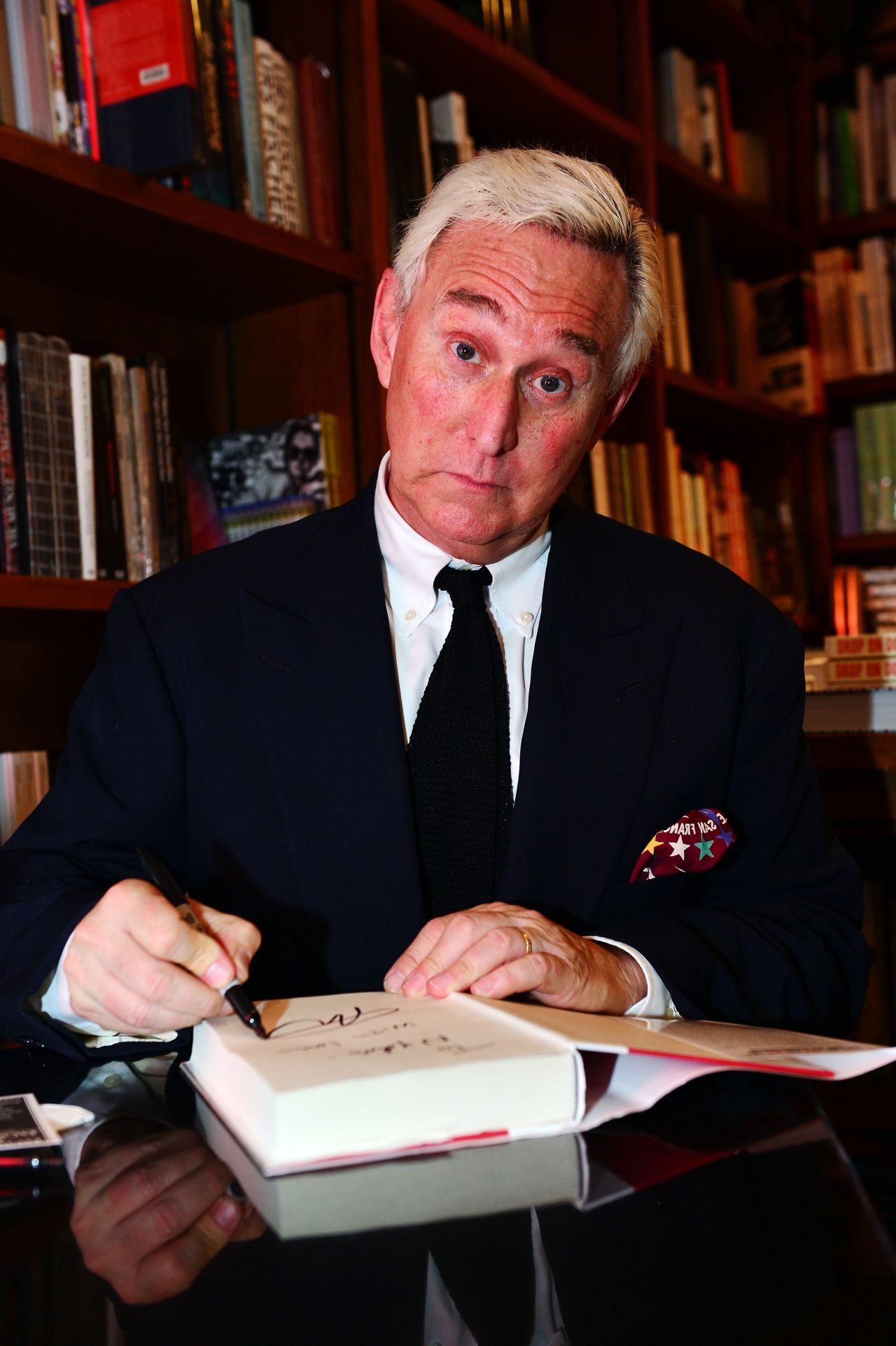 Stone signs copies of his book, "The Man Who Killed Kennedy: The Case Against LBJ" in December 2013.