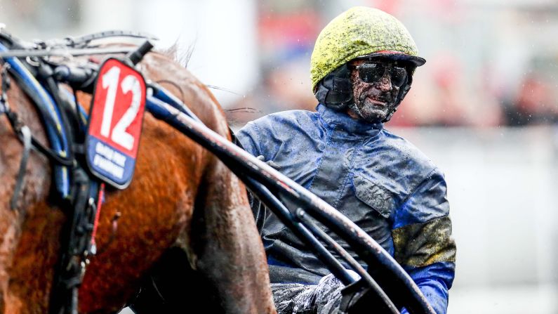 Jean-Michel Bazire is covered in mud during a harness race in Paris on Sunday, January 27.