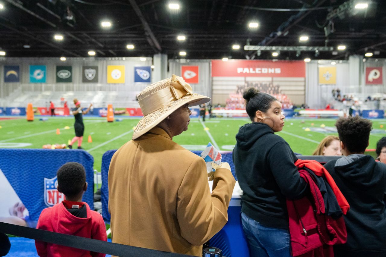 Ma Ellis of Atlanta (in hat) watches as kids prepare to take the field for mock drills at the Super Bowl Experience in the Georgia World Congress Center.
