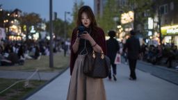 A woman looks at a mobile phone as she stands on a path in the popular Yeonnam-dong area of Seoul on October 15, 2016. / AFP / Ed Jones        (Photo credit should read ED JONES/AFP/Getty Images)