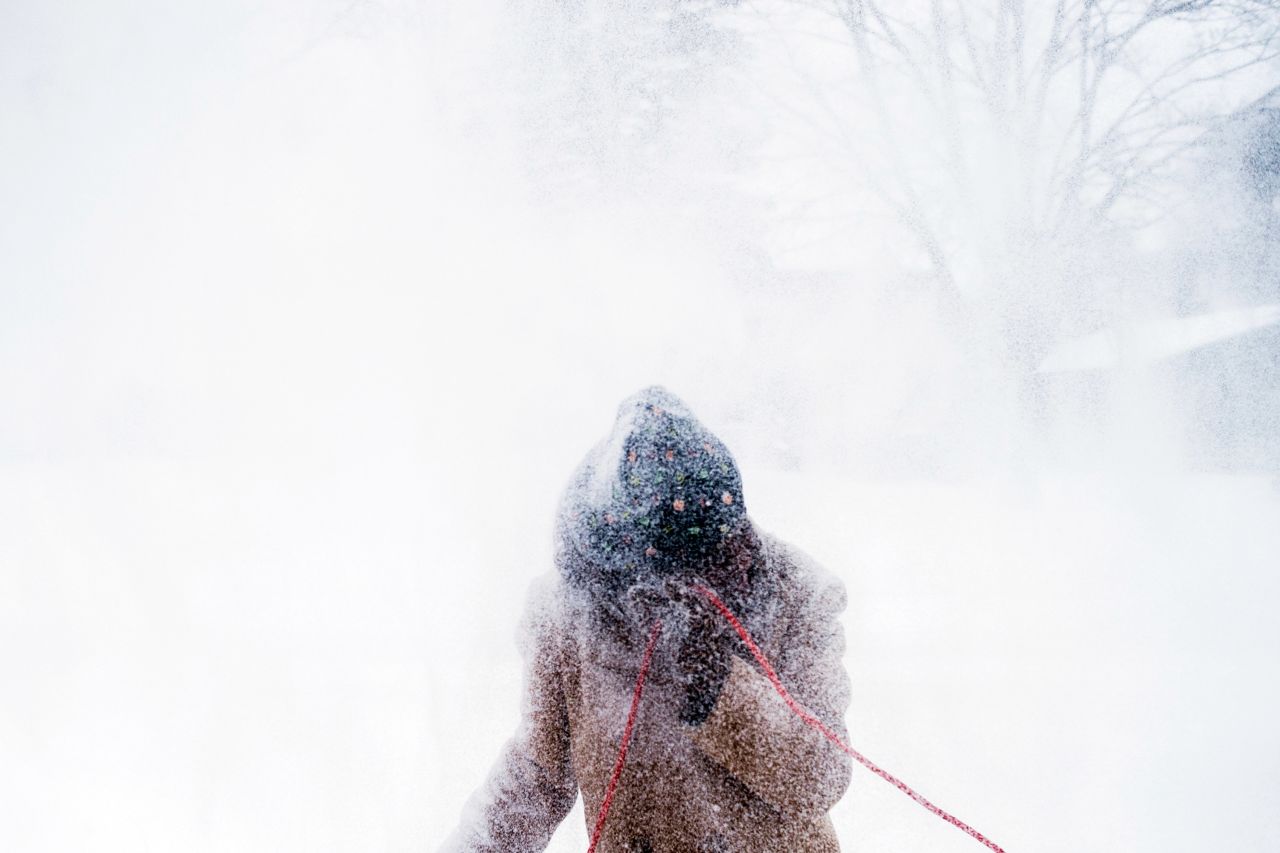 Sarah Allen gets a faceful of snow as she clears her driveway and sidewalks with a snowblower in Flint, Michigan.