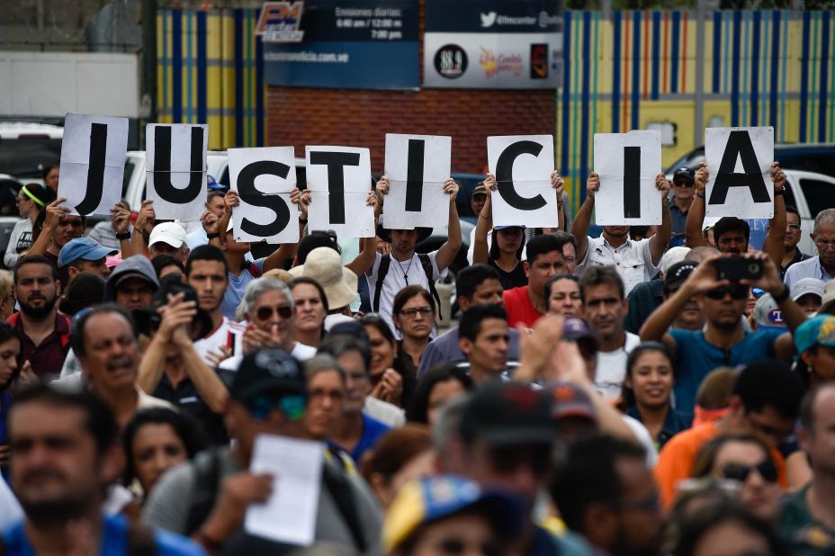 Supporters of Venezuela's opposition hold up letters that read "Justice" at a rally to hear Guaido speak in Caracas on Saturday, January 26.