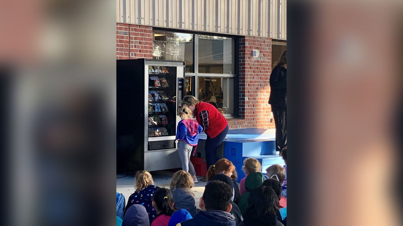 A student uses the book vending machine for the first time. 