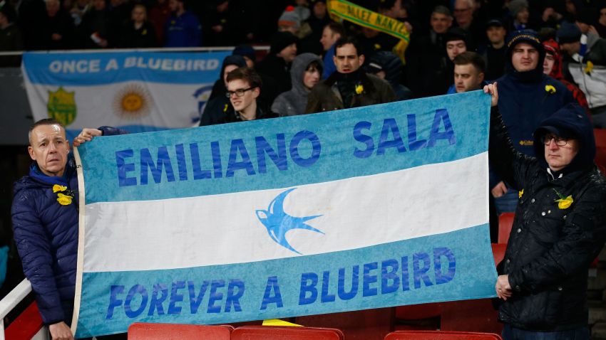 Fans hold up a banner in the colours of the Argentina flag honouring Cardiff's missing Argentinian player Emiliano Sala ahead of the English Premier League football match between Arsenal and Cardiff City at the Emirates Stadium in London on January 29, 2019. - A shipwreck hunter hired by the family of missing footballer Emiliano Sala to look for his missing plane said he was planning to begin an underwater search on Sunday. David Mearns of Bluewater Recoveries said on Monday, January 28, 2019, that two fishing boats were searching the sea around the island of Guernsey as part of the search. (Photo by Ian KINGTON / AFP) / RESTRICTED TO EDITORIAL USE. No use with unauthorized audio, video, data, fixture lists, club/league logos or 'live' services. Online in-match use limited to 120 images. An additional 40 images may be used in extra time. No video emulation. Social media in-match use limited to 120 images. An additional 40 images may be used in extra time. No use in betting publications, games or single club/league/player publications. /         (Photo credit should read IAN KINGTON/AFP/Getty Images)