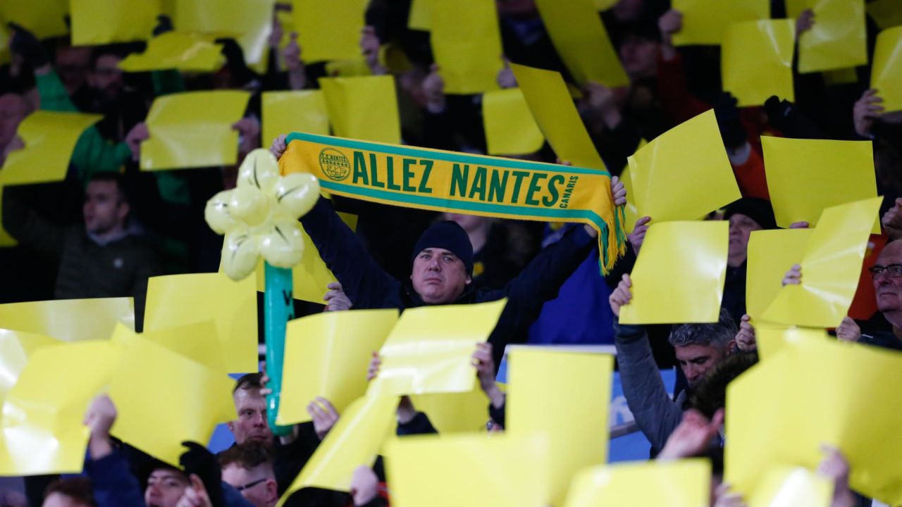 Fans hold up yellow banners and a Nantes scarf.