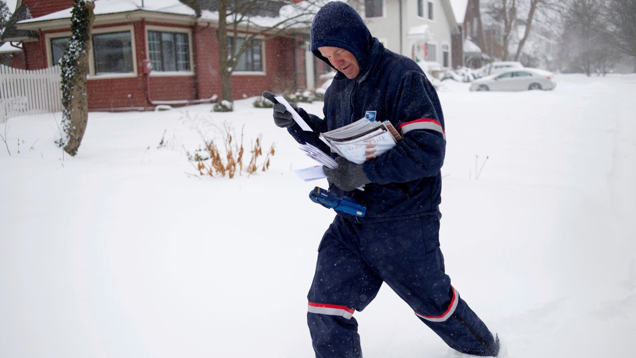A Postal Service carrier delivers mail Monday in East Grand Rapids, Michigan. East Grand Rapids is one of the ares where mail service was suspended Wednesday.