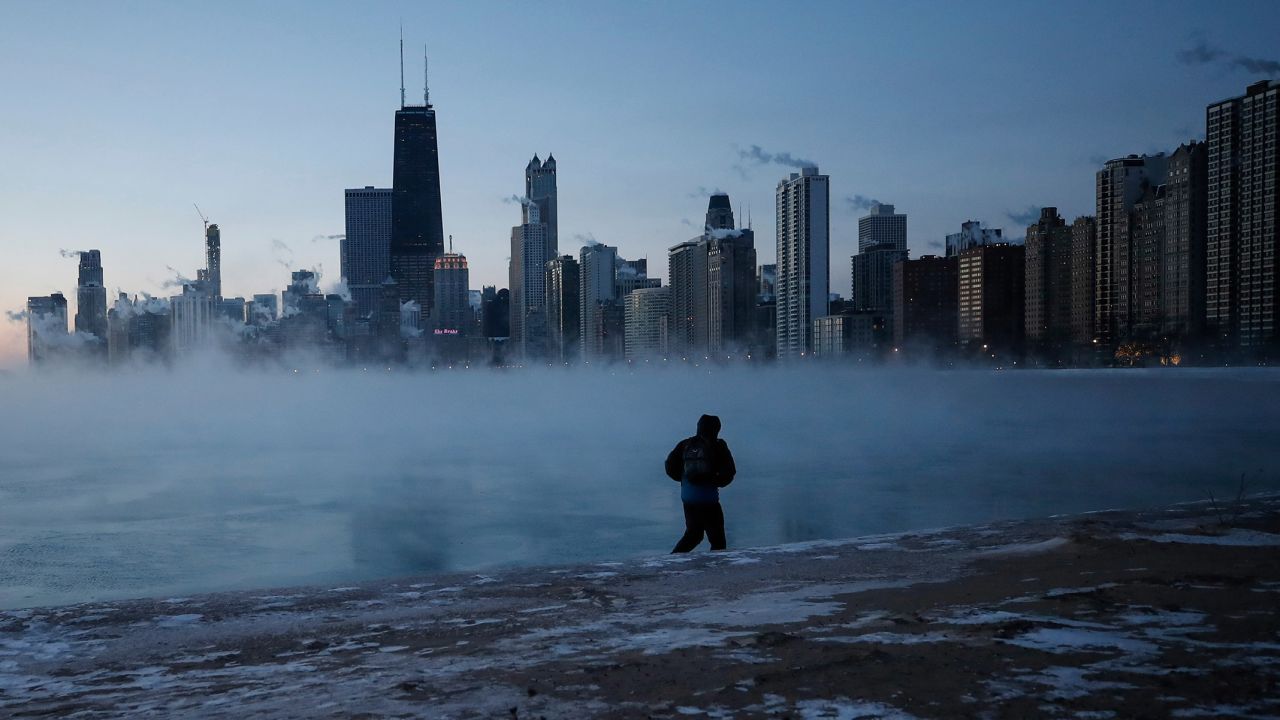 A man walks on Chicago's North Avenue Beach as the sun rises over Lake Michigan on January 30.