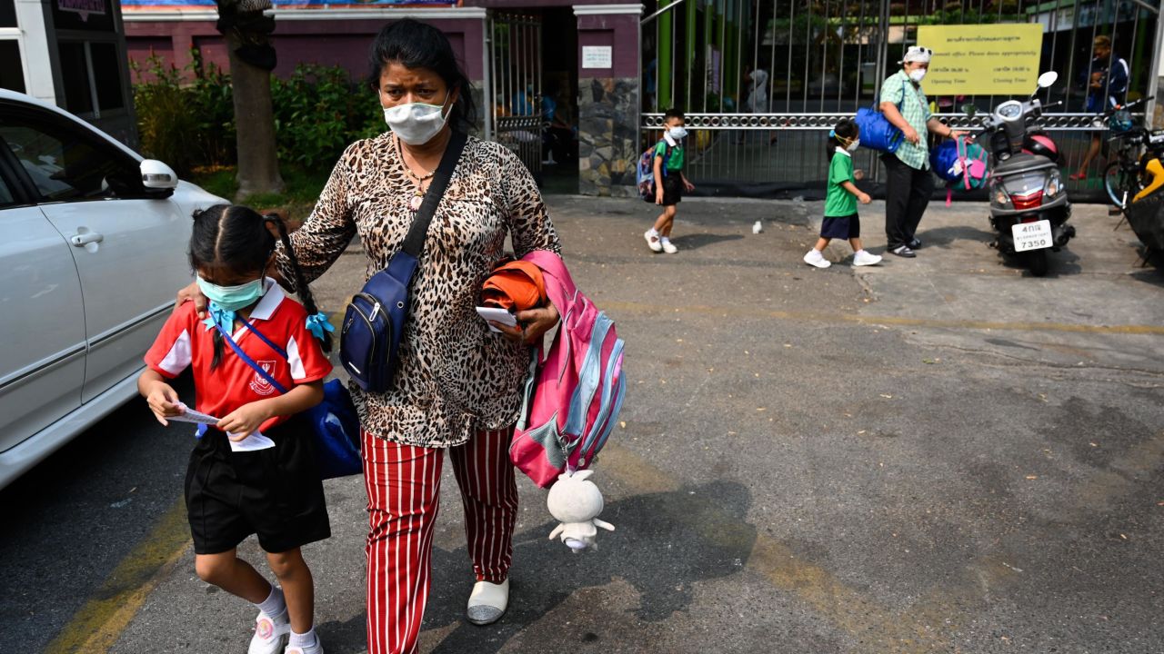 A woman picks up a child from school early due to toxic levels of air pollution in Bangkok on Wednesday. 