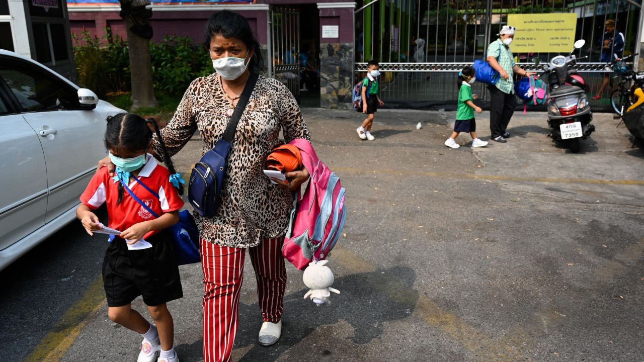 A woman picks up a child from school early due to toxic levels of air pollution in Bangkok on Wednesday.