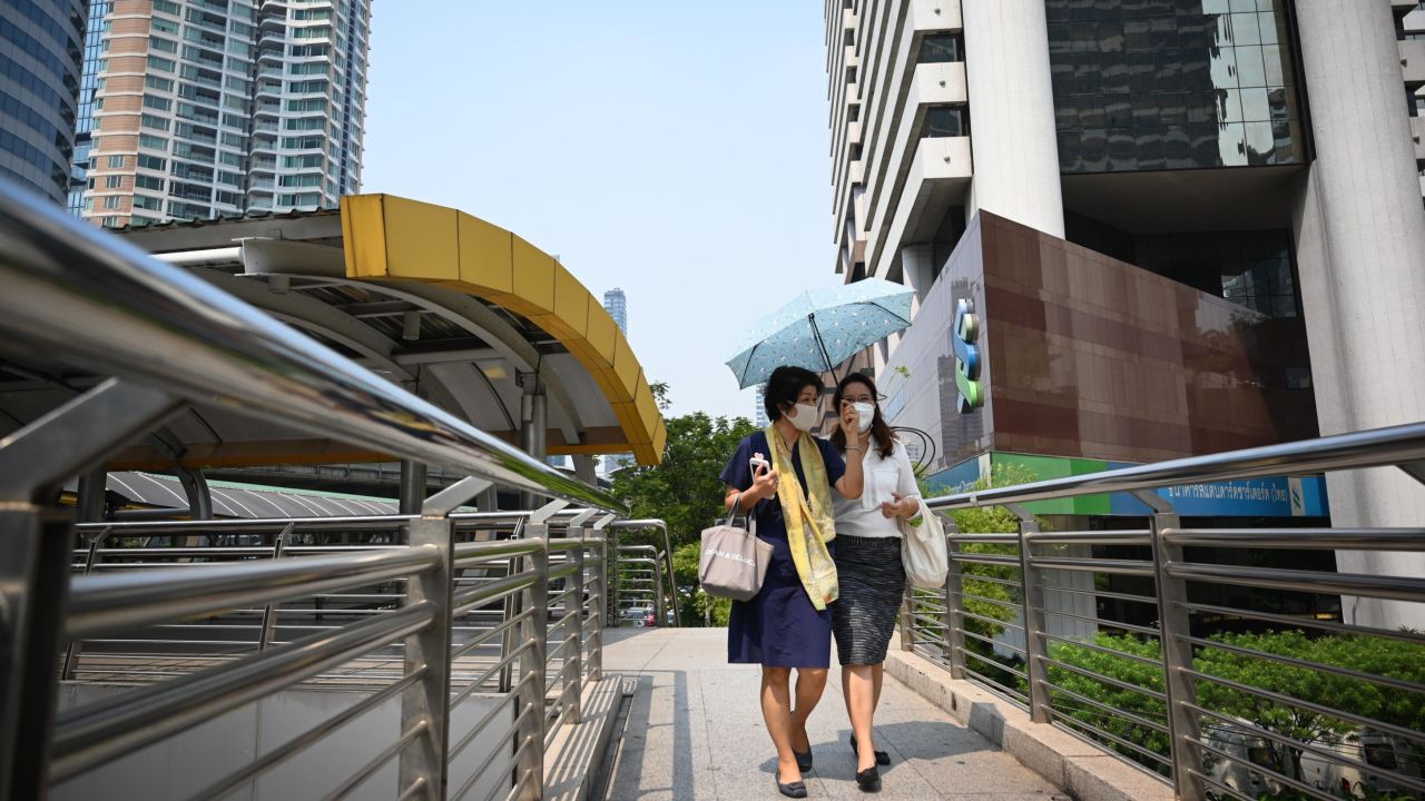 People wearing face masks walk on a bridge in Bangkok's central business district.