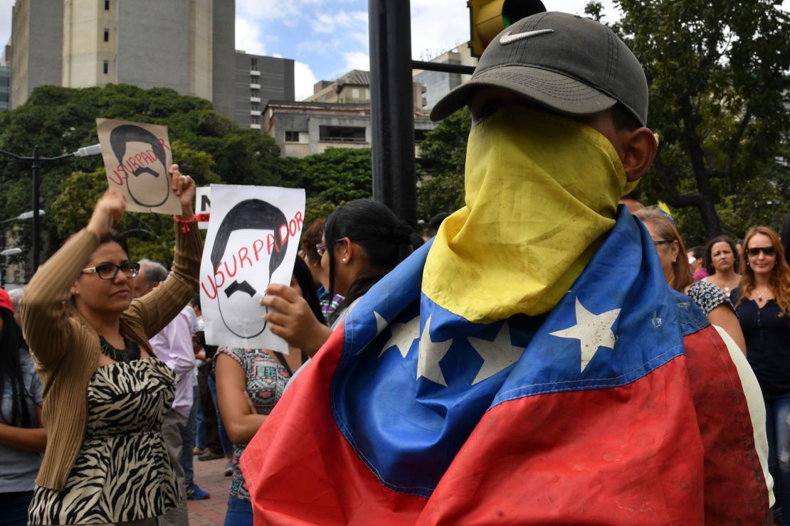 An opposition demonstrator covers his face with a Venezuelan national flag, during a protest against President Nicolas Maduro on January 30, 2019. 