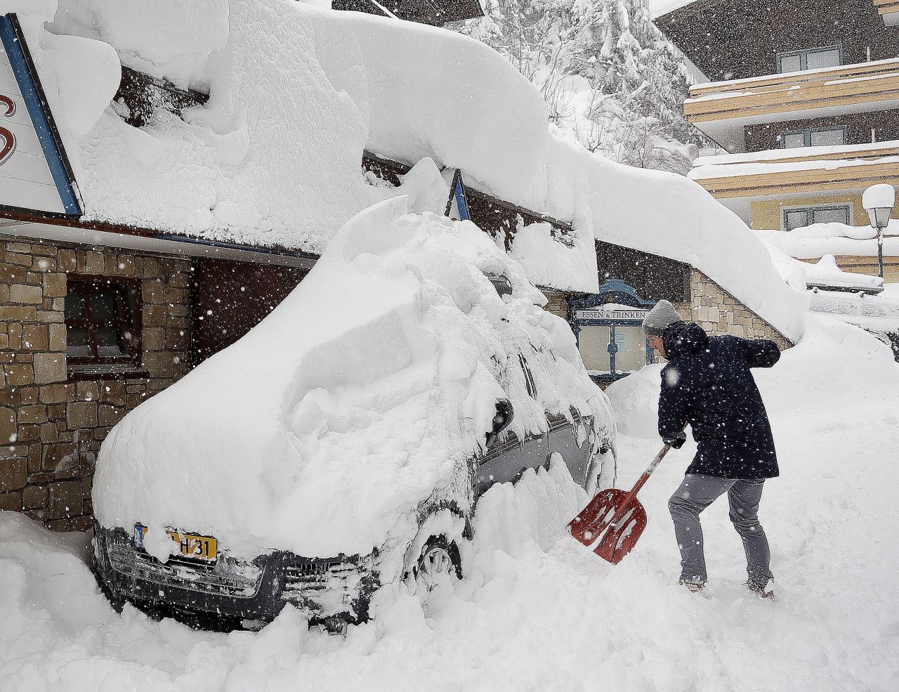 A tourist removes snow from a vehicle in Filzmoos, Austria, on Saturday, January 5.
