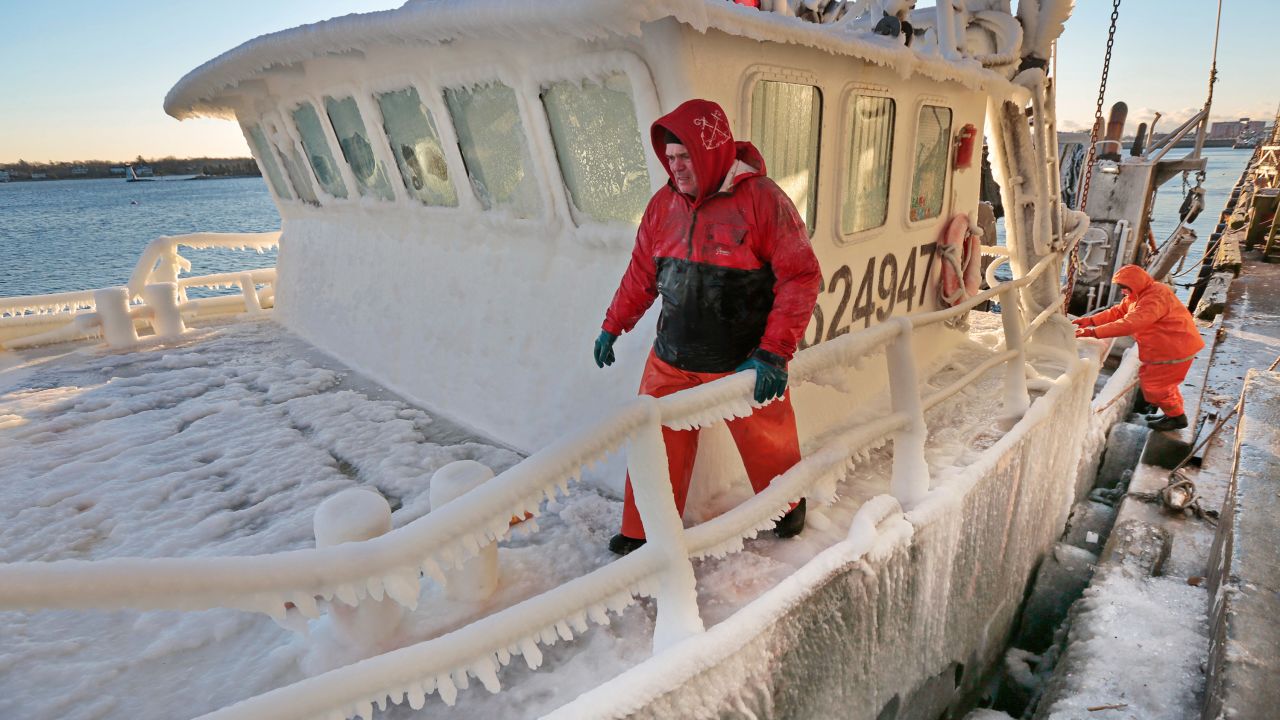 Mike Calen, left, and Steve Goyette, right, prepare to tie off as the ice-covered fishing boat Buzzards Bay arrives in the harbor in New Bedford, Massachusetts on Thursday.
