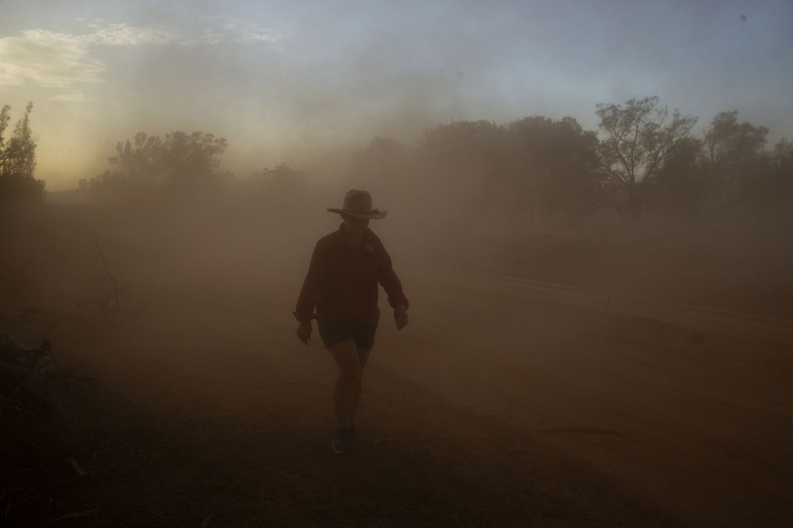 An Australian farmer walks through a cloud of dust on her property on January 16.