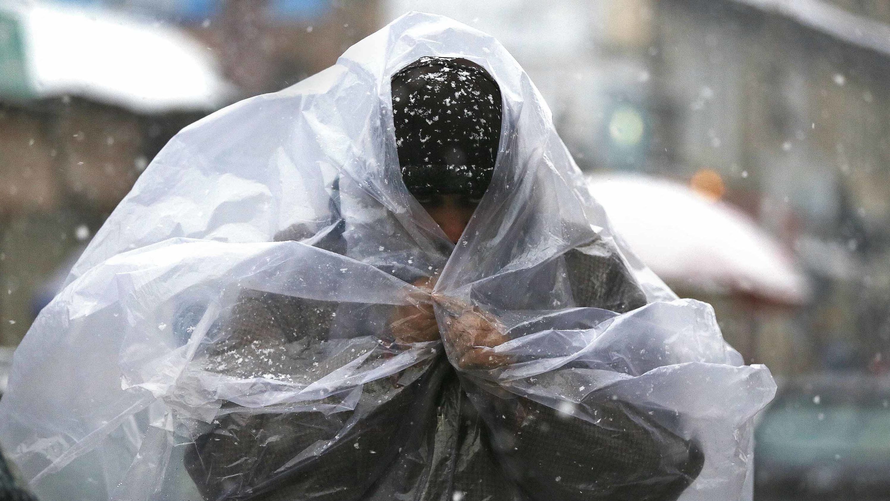 A man covers himself with a plastic sheet during snowfall in Srinagar in Indian-controlled Kashmir on Thursday, January 31. 