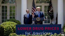 U.S. President Donald Trump, right, speaks as Alex Azar, secretary of Health and Human Services (HHS), listens during an event on lowering drug prices in the Rose Garden of the White House in Washington, D.C., U.S., on Friday, May 11, 2018. Trump is proposing a sweeping effort to bring down U.S. drug prices in a long-awaited plan meant to fulfill a promise he has been pushing since his bid for the White House. Photographer: Andrew Harrer/Bloomberg via Getty Images