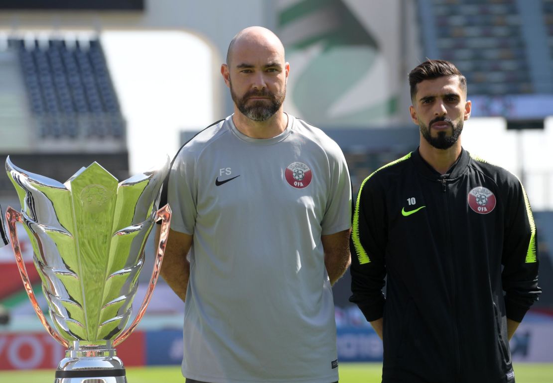 Qatar's head coach Felix Sanchez with player Hasan Al Haydos pose next to the Asian Cup trophy ahead of the final.