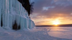 The sun rises over a frozen Lake Superior and reflects the blue hues, on Grand Island's ice curtains. Offshore from Munising Michigan; Shutterstock ID 790093693; Job: -