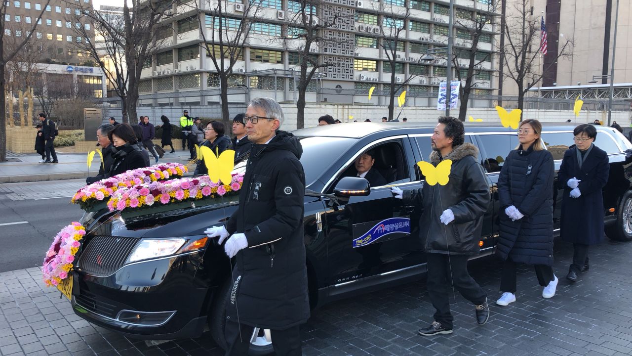 A car carrying Kim Bok-dong's casket drives through downtown Seoul.