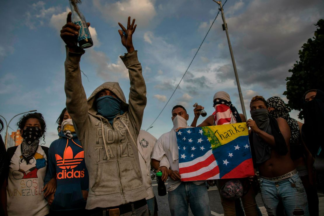 Anti-government protesters prepare to sing Venezuela's national anthem while blocking a highway in Caracas on February 2, 2019.