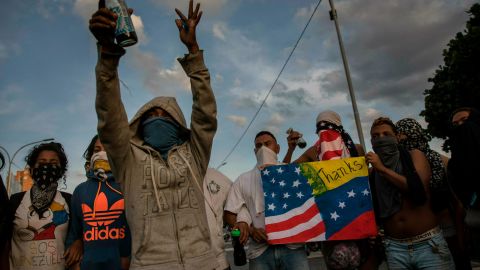 Anti-government protesters prepare to sing Venezuela's national anthem while blocking a highway in Caracas on February 2, 2019.