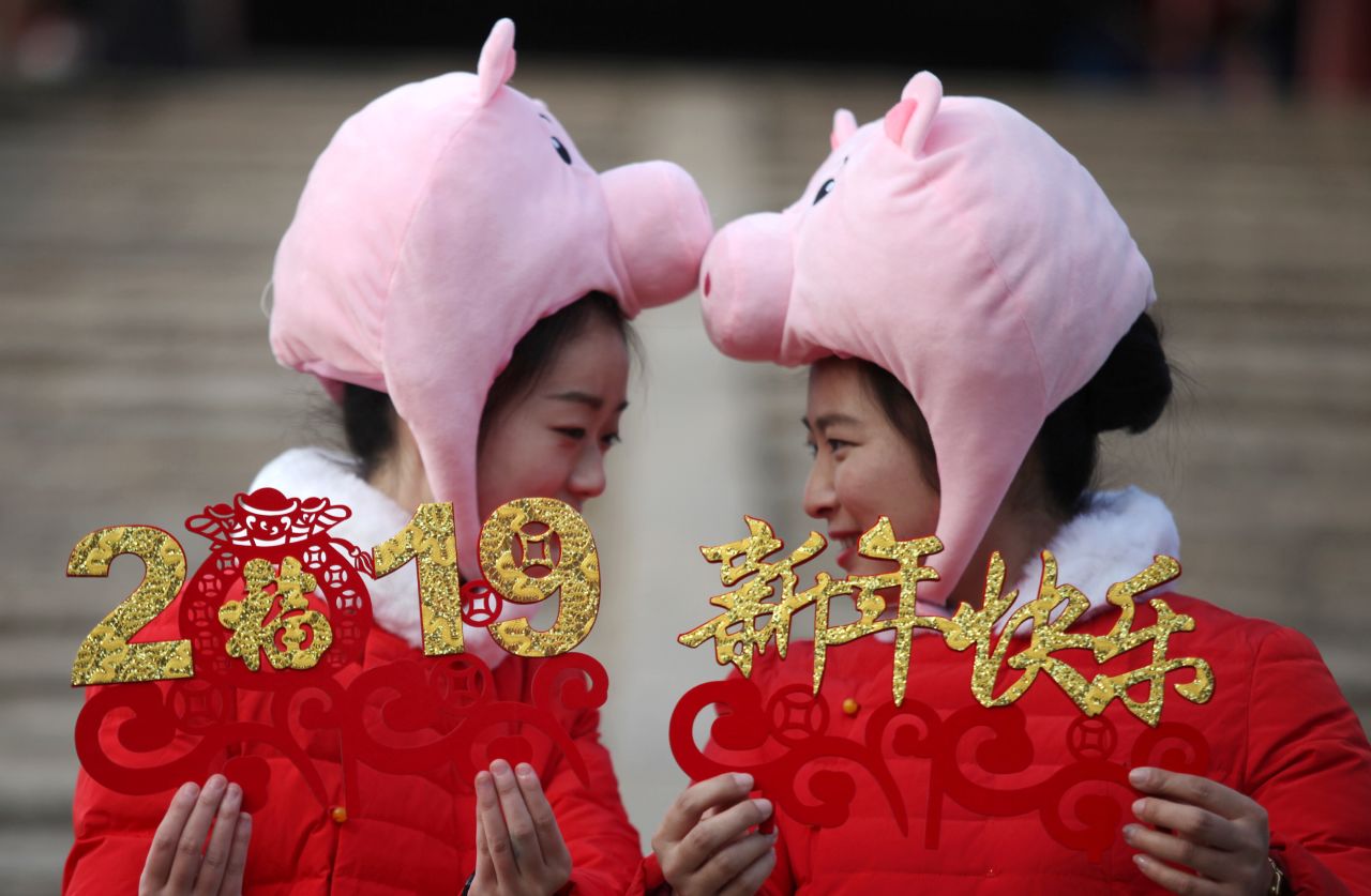 Tourist guides wearing pig hats and matching red coats in Yangzhou, Jiangsu province.