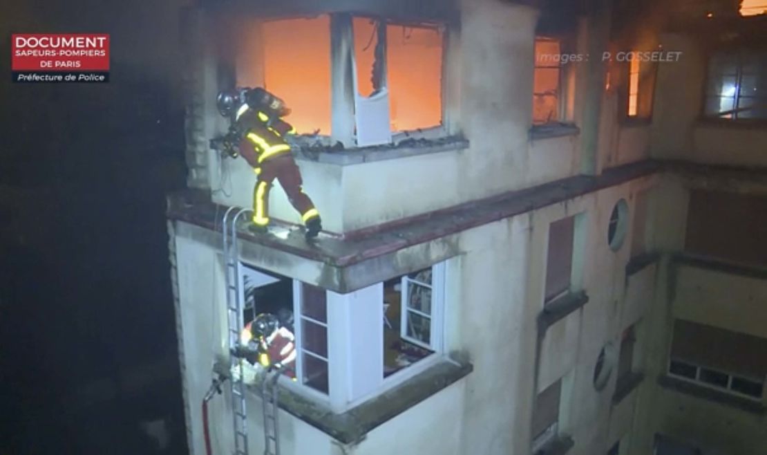 Firemen scale the top floors of the burning building.