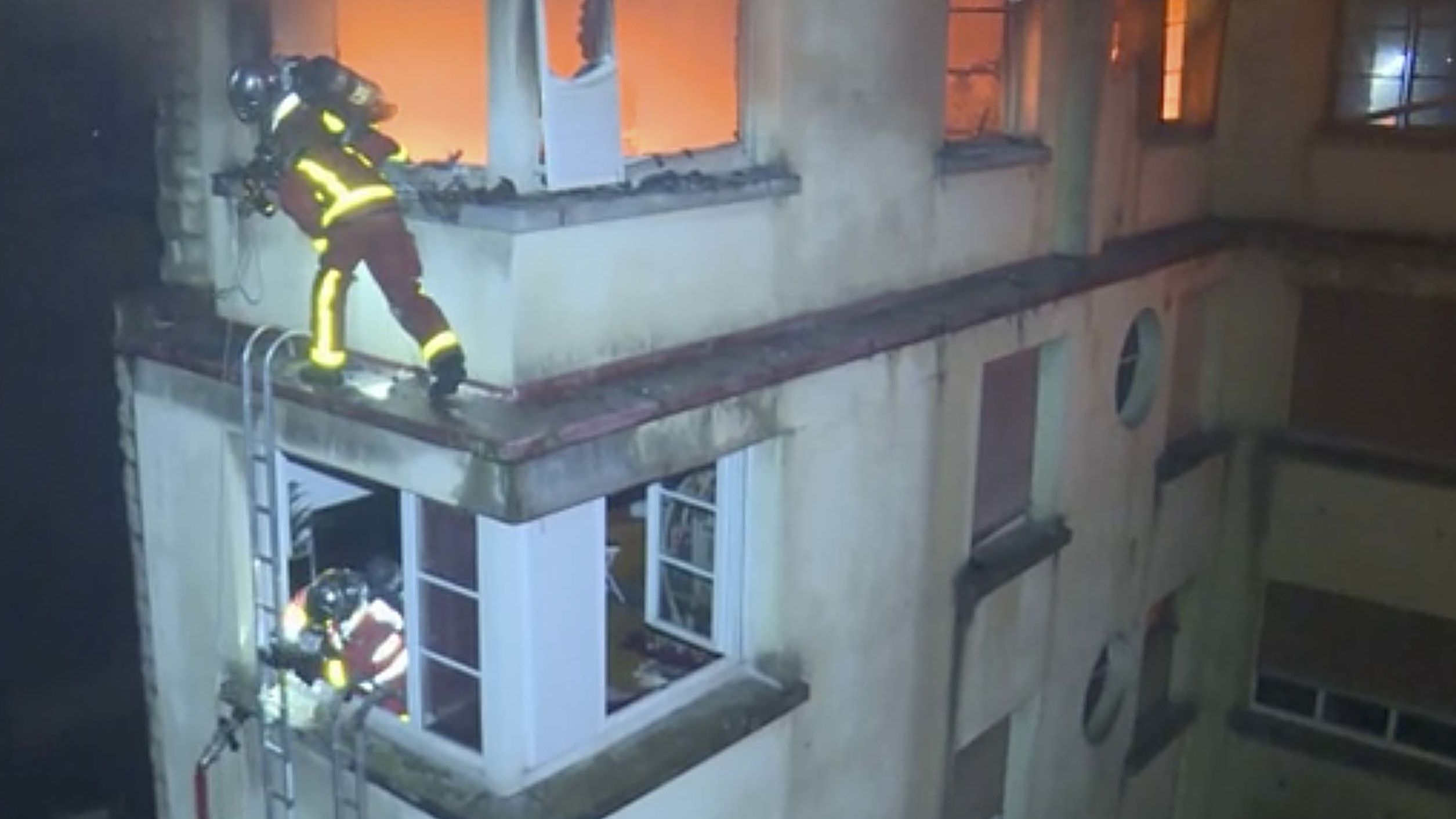 Los bomberos escalan los pisos superiores del edificio en llamas.