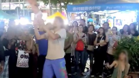 A screenshot from a video taken by a Facebook user, which purportedly shows a Russian tourist swinging his infant child around by the ankles during a street performance in the Bukit Bintang area of Kuala Lumpur, Malaysia. Faces have been blurred by CNN. 
