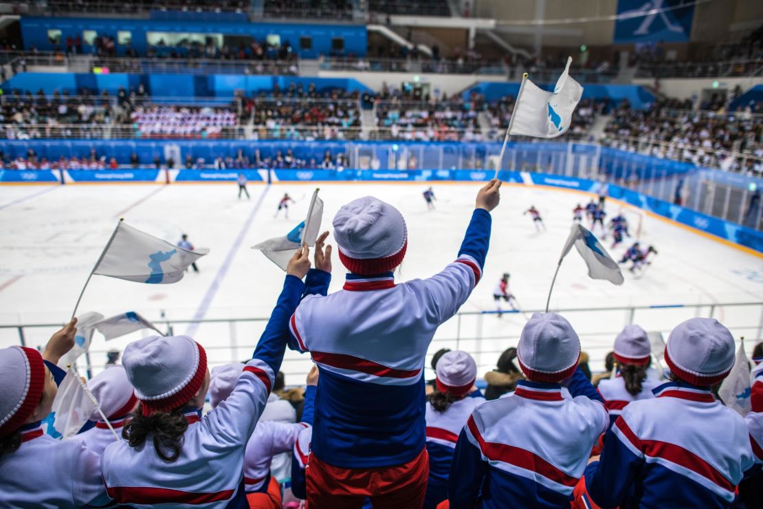 North Korean cheerleaders wave unified Korean flags.