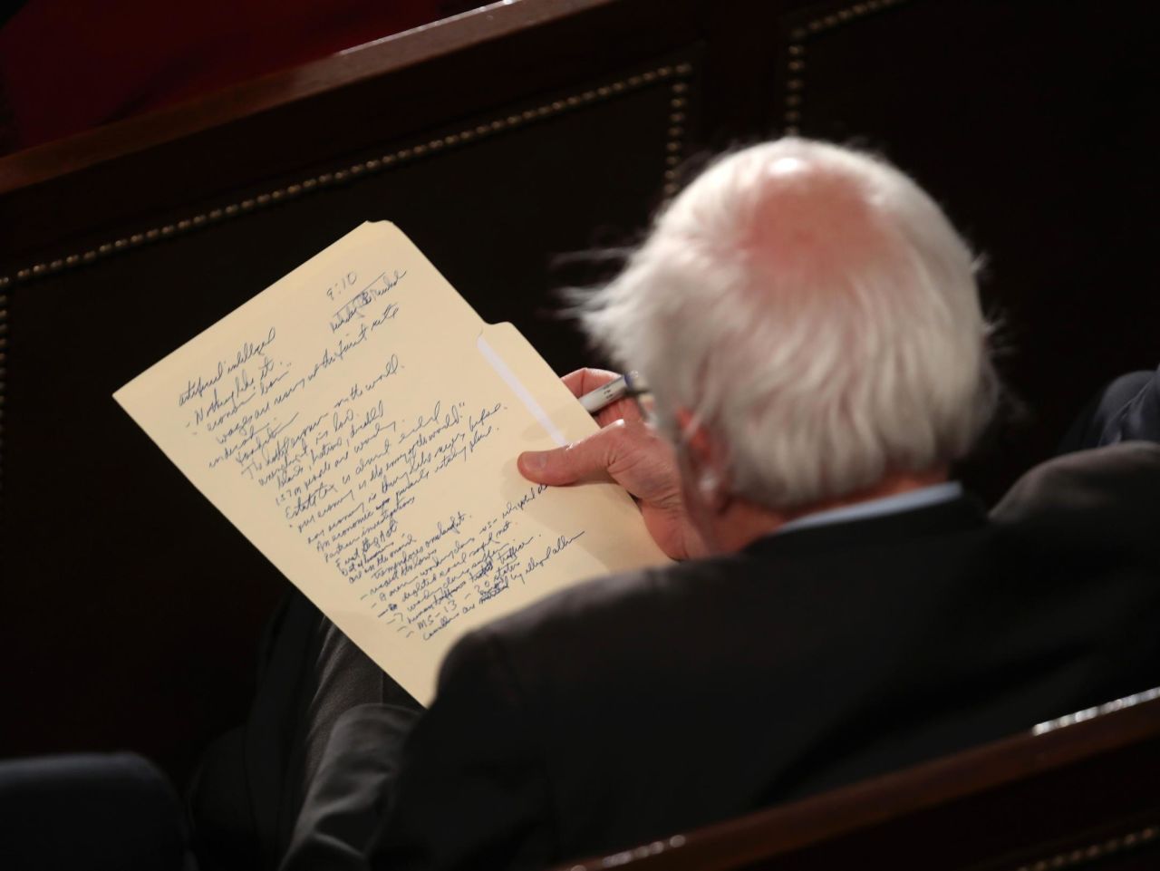 US Sen. Bernie Sanders looks at his notes as he watches the speech from inside the House chamber.